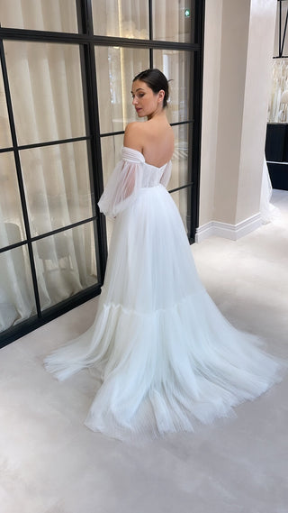 Elegant white wedding dress featuring a sweetheart neckline, airy tulle fabric, and off-the-shoulder long sleeves, ideal for timeless and contemporary bridal looks