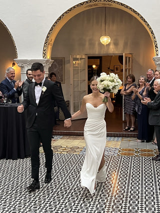 Minimalist ivory strapless wedding dress with a sweetheart neckline, draped bodice, and flowing train, designed for contemporary and stylish weddings