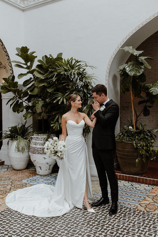 Sophisticated strapless bridal gown in ivory featuring a sweetheart neckline, sleek silhouette, and elegant draping, paired with a sheer veil, perfect for classic wedding ceremonies