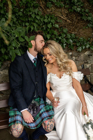 Elegant ivory bridal dress featuring off-the-shoulder floral detailing, luxurious satin fabric, and a sweeping train, ideal for sophisticated and romantic wedding celebrations