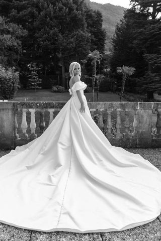 Breathtaking off-the-shoulder bridal gown with a dramatic cathedral-length train, perfect for an elegant and timeless wedding look