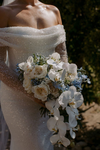 Romantic fitted wedding dress in ivory with shimmering sequins, off-the-shoulder detail, lace sleeves, and a flowing silhouette, perfect for elegant and glamorous bridal occasions