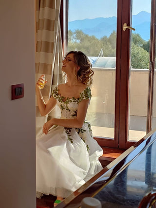 Romantic ivory bridal dress adorned with floral lace details, off-the-shoulder puff sleeves, and a tea-length silhouette, perfect for vintage-inspired celebrations