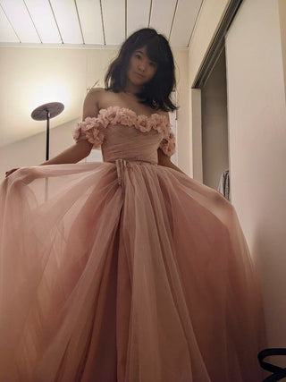 Chic pink bridal gown with a layered tulle skirt, floral detailing on off-the-shoulder sleeves, and a corset-inspired bodice, crafted for modern princess-inspired weddings