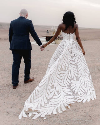 Sophisticated ivory wedding dress with a strapless bodice, intricate leaf-pattern cutouts, and a flowing A-line silhouette, designed for timeless and nature-inspired weddings