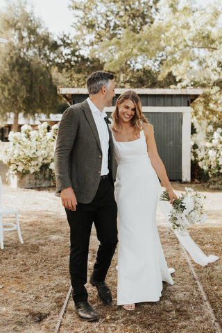 Sleek and sophisticated bridal dress with a structured bodice and simple elegance, paired with a romantic floral bouquet