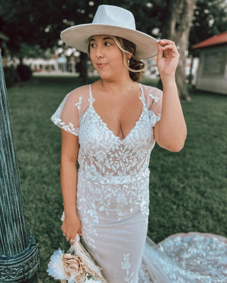 Elegant embroidered lace wedding dress with cap sleeves and a flowing train, perfect for outdoor and boho-themed ceremonies