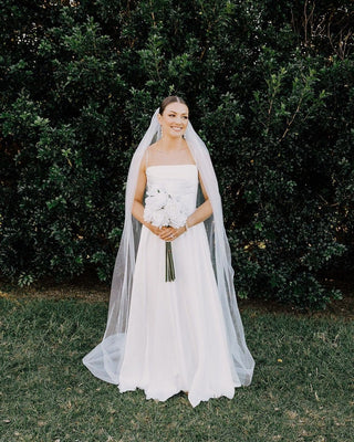 Timeless wedding dress with clean lines, lightweight fabric, and a soft tulle veil, creating a serene bridal look for natural settings.