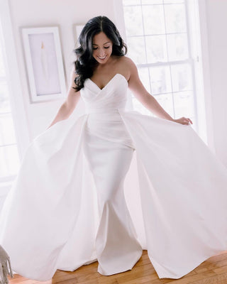 Romantic ivory strapless wedding gown adorned with draped fabric details, sweetheart neckline, and a voluminous A-line skirt with a sweeping train, perfect for traditional bridal celebrations