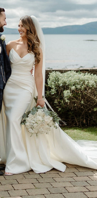 Sophisticated ivory strapless dress with a sweetheart neckline, sleek bodice, and dramatic train, designed for modern yet timeless wedding aesthetics