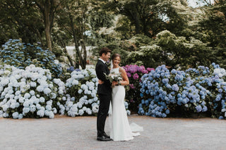 Minimalist ivory wedding dress featuring a high neckline, clean lines, and a fitted design with a classic train, perfect for elegant and refined ceremonies