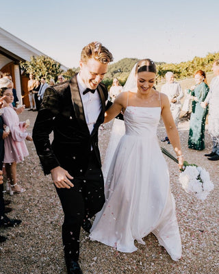 Classic white bridal gown with delicate spaghetti straps and a modern veil, ideal for outdoor weddings by the water.