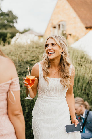 Elegant sleeveless wedding gown featuring detailed beading and a curve-enhancing silhouette, paired with a square neckline for a modern yet timeless bridal look, perfect for garden or city weddings