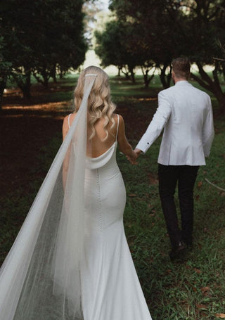 Classic and refined bridal gown with a cowl-draped front, flowing fabric, and a soft train, embodying effortless elegance for a timeless bridal look