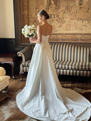 Chic ivory bridal dress featuring a strapless sweetheart neckline, ruched detailing, and a classic A-line silhouette with a sweeping train, ideal for sophisticated and modern weddings