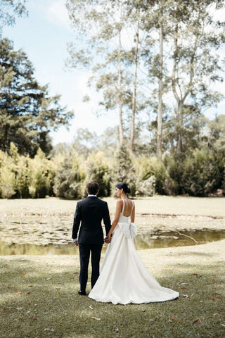 Modern bridal elegance with a simple yet striking wedding dress, featuring a backless design and voluminous bow accent