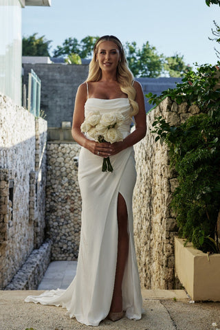 Timeless white satin wedding gown featuring a ruched bodice, thin spaghetti straps, and a daring thigh-high slit, exuding modern elegance.