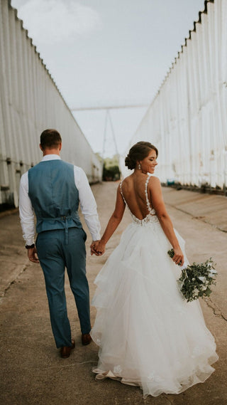 Bride wearing a stunning lace wedding dress with a plunging neckline and tulle overlay, ideal for summer weddings and rustic celebrations