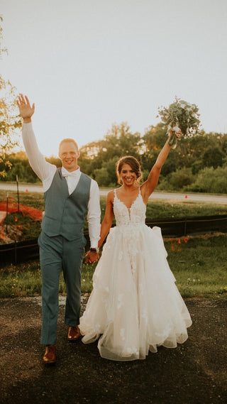 Elegant lace wedding gown with a deep V-neckline, intricate floral embroidery, and a flowing A-line skirt, perfect for romantic outdoor ceremonies