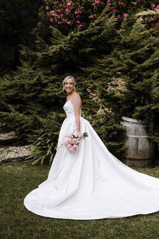 Modern satin wedding gown with a sweetheart neckline, subtle ruching across the bodice, and a voluminous A-line silhouette, ideal for formal ceremonies.