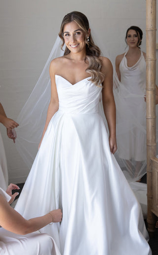 Elegant satin wedding dress with a strapless sweetheart neckline and ruched bodice, complemented by a classic A-line skirt, perfect for a timeless bridal look.