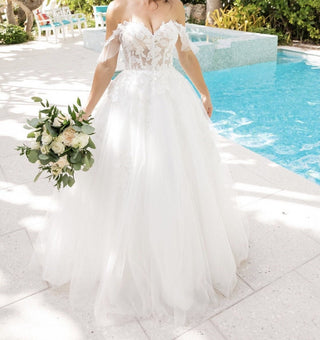 Elegant off-the-shoulder wedding gown with a corset-style bodice and flowing layers of soft white tulle