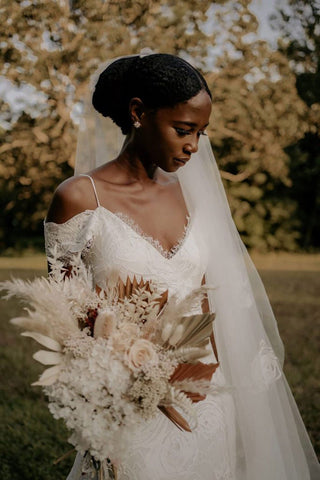 Delicate lace wedding gown with a deep V-neckline, spaghetti straps, and a high front slit, perfect for modern beach ceremonies.