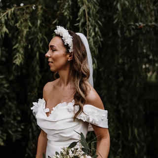 Romantic ivory satin gown with floral embellishments on the off-the-shoulder neckline, a fitted silhouette, and a flowing train, perfect for classic and elegant weddings