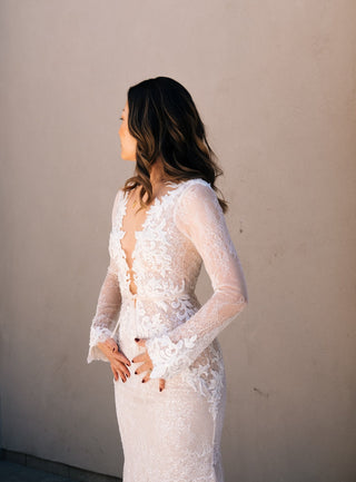 Elegant ivory bridal dress featuring detailed lacework, deep V-plunge neckline, sleeveless A-line design, and flowing tulle skirt, ideal for classic wedding celebrations