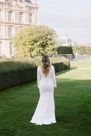 With its flawless combination of clean lines and intricate detailing, this white dress is designed to make a statement. The full sleeves provide classic bridal elegance, while the sheer lace side panels create a sultry yet sophisticated contrast. Perfect for an elegant winter or autumn wedding, the dress' simple yet bold design makes it a standout piece that exudes both luxury and grace