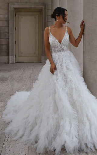 Romantic wedding dress with a plunging neckline, floral lace bodice, and cascading layers of soft tulle