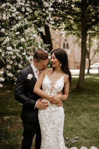 Chic and sophisticated lace gown with a deep neckline, floral embellishments, and glittering sequin accents, ideal for formal weddings or evening receptions