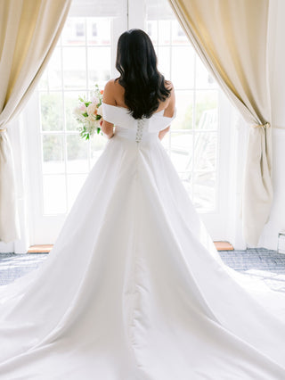 Sleek satin wedding gown with a contemporary off-the-shoulder neckline and clean lines, exuding effortless sophistication for the modern bride