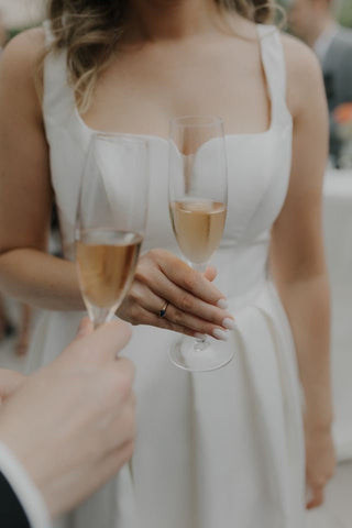 Elegant white bridal gown featuring a strapless bodice, pleated satin detailing, and a thigh-high slit, ideal for a chic and sophisticated wedding, complemented by soft curls and a bouquet of blush-toned flowers