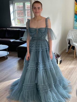 Romantic tiered blue dress with off-shoulder tulle accents, embodying contemporary elegance and sophistication