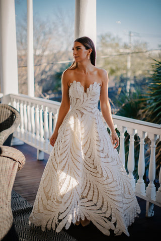 Strapless ivory A-line gown with intricate leaf-patterned cutout design, flowy floor-length silhouette, and modern minimalist aesthetic, perfect for elegant weddings and formal occasions