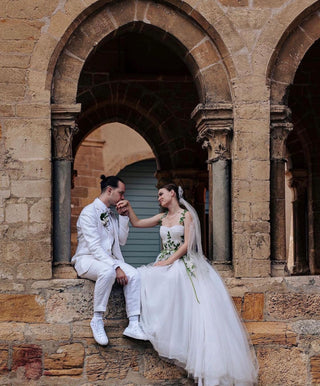 Charming bridal gown with intricate green foliage accents and floral embellishments, ideal for outdoor or garden-themed weddings