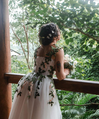 Romantic white tulle dress adorned with leafy embroidery and floral accents, creating a magical and natural bridal look