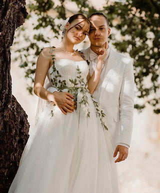 Ethereal wedding dress featuring botanical embroidery with cascading green vines and petite white flowers, blending modern and bohemian elegance