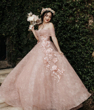 Ethereal pink gown adorned with cascading 3D floral details, an off-the-shoulder tulle wrap, and a voluminous skirt, ideal for whimsical celebrations or springtime events