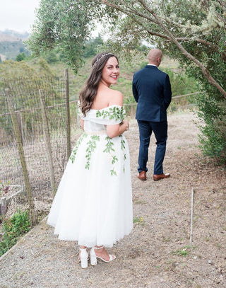 Sophisticated ivory wedding gown with floral embroidery, sweetheart neckline, puff off-the-shoulder sleeves, and a tea-length A-line design, ideal for elegant and classic bridal occasions