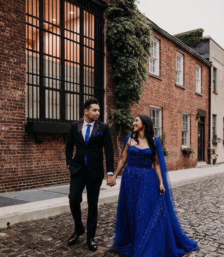 Elegant cobalt blue celestial gown with sparkling gold star details, floor-length A-line silhouette, sweetheart neckline, and long cape sleeves, ideal for wedding guests and evening parties