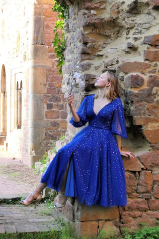 Elegant cobalt blue celestial dress with gold glitter starry details, deep V-neckline, high slit, and puff half sleeves, tailored for special events, prom nights, and evening galas