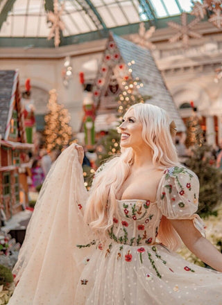 Ethereal off-the-shoulder cream gown adorned with vibrant floral embroidery and flowing tulle, perfect for whimsical weddings