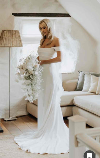 Graceful off-shoulder wedding dress with flowing train, perfect for a romantic and timeless bridal look