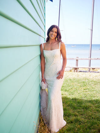 Romantic ivory gown adorned with sequin embroidery, open low-back design, and a floor-length fit-and-flare style, perfect for elegant and fairy-tale-inspired weddings