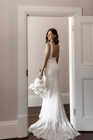 Chic ivory bridal gown with shimmering sequin details, low backless design, and a flowing fit-and-flare silhouette, tailored for glamorous and contemporary weddings