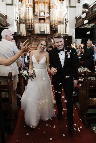 Sophisticated white ballgown with a structured V-neck bodice, airy layers of tulle, and dainty spaghetti straps, designed for brides who want a classic yet contemporary style