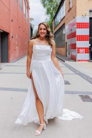 Simple and elegant white wedding dress with a contemporary design and a romantic veil, perfect for intimate outdoor nuptials.