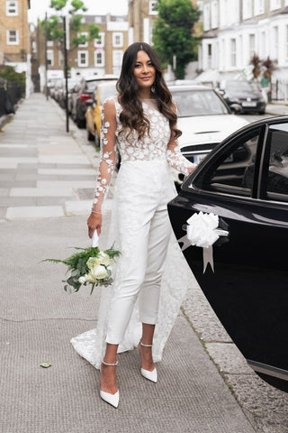 Romantic white jumpsuit adorned with floral lace embroidery, sheer sleeves, and a detachable lace overskirt, perfect for fashion-forward and minimalist weddings